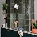 White ceramic sheep head sculpture mounted on dark green tiled wall from foundry porcelain smeraldo collection