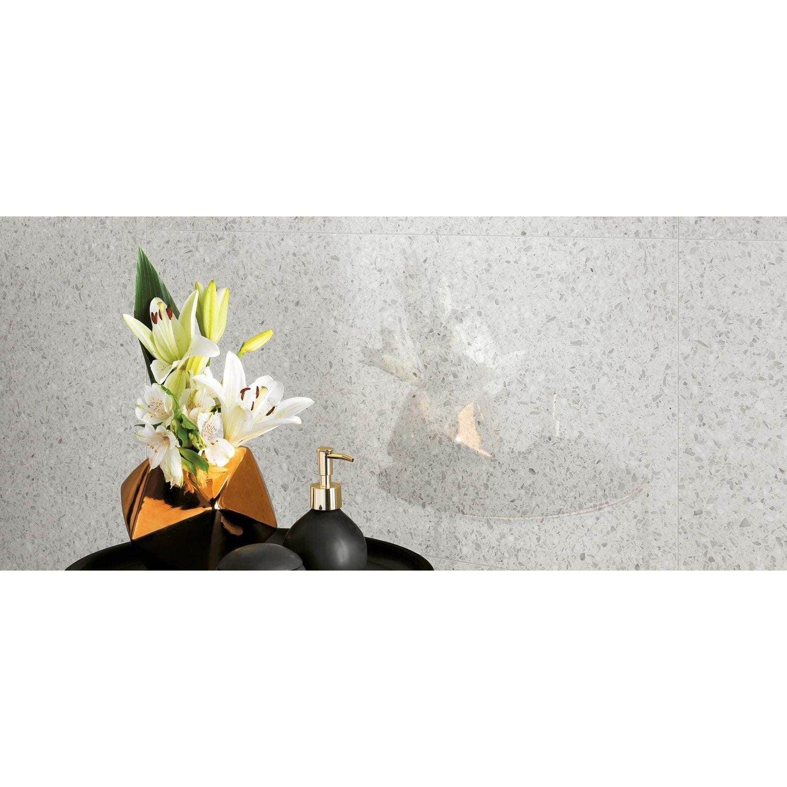Gold geometric vase with white lilies and green leaves on gemstones terrazzo white matt 60 x 60cm tile surface