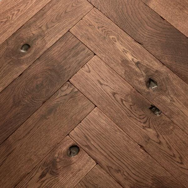Goodrich spiced oak dark brown hardwood floor planks with visible grain and knots in a herringbone pattern