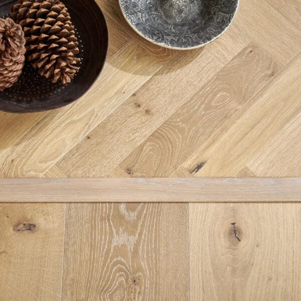 Goodrich white smoked oak light-colored hardwood floor with herringbone pattern and natural wood grain texture