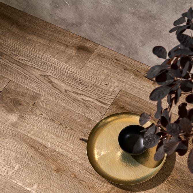 Golden hammered tray holding a black bowl and dark foliage featuring harlech biscotti oak design