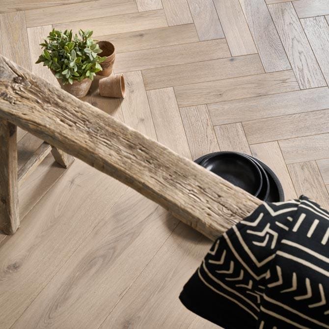 Weathered wooden beam with natural grain and rustic texture resting diagonally on harlech feather oak herringbone floor