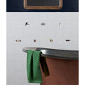 Green herringbone cotton towel draped over bathtub rim in menagerie ceramic by michael angove product setting