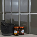 Two glass jars of mackays jam with copper lids on a metro dark grey gloss surface featuring orange marmalade and strawberry preserves