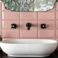 White oval vessel sink with matte black faucet and handles against pink tiled walls in metro pink gloss design