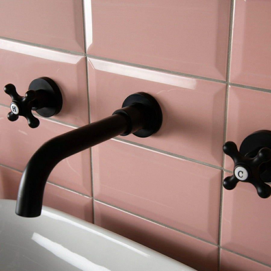 Black matte-finish wall-mounted faucet with cross-shaped handles marked h and c in metro pink gloss design