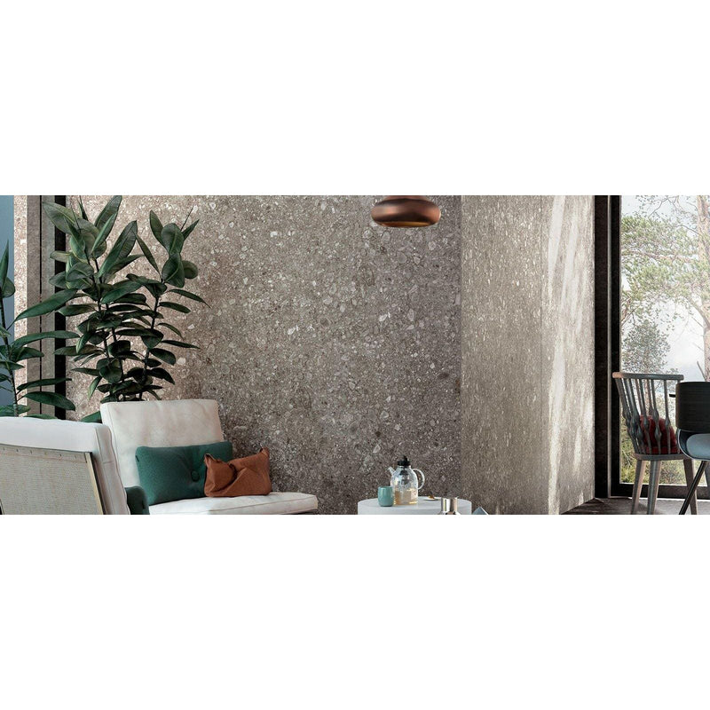 Norway Gra Matt grey terrazzo-effect tiles with a white woven armchair