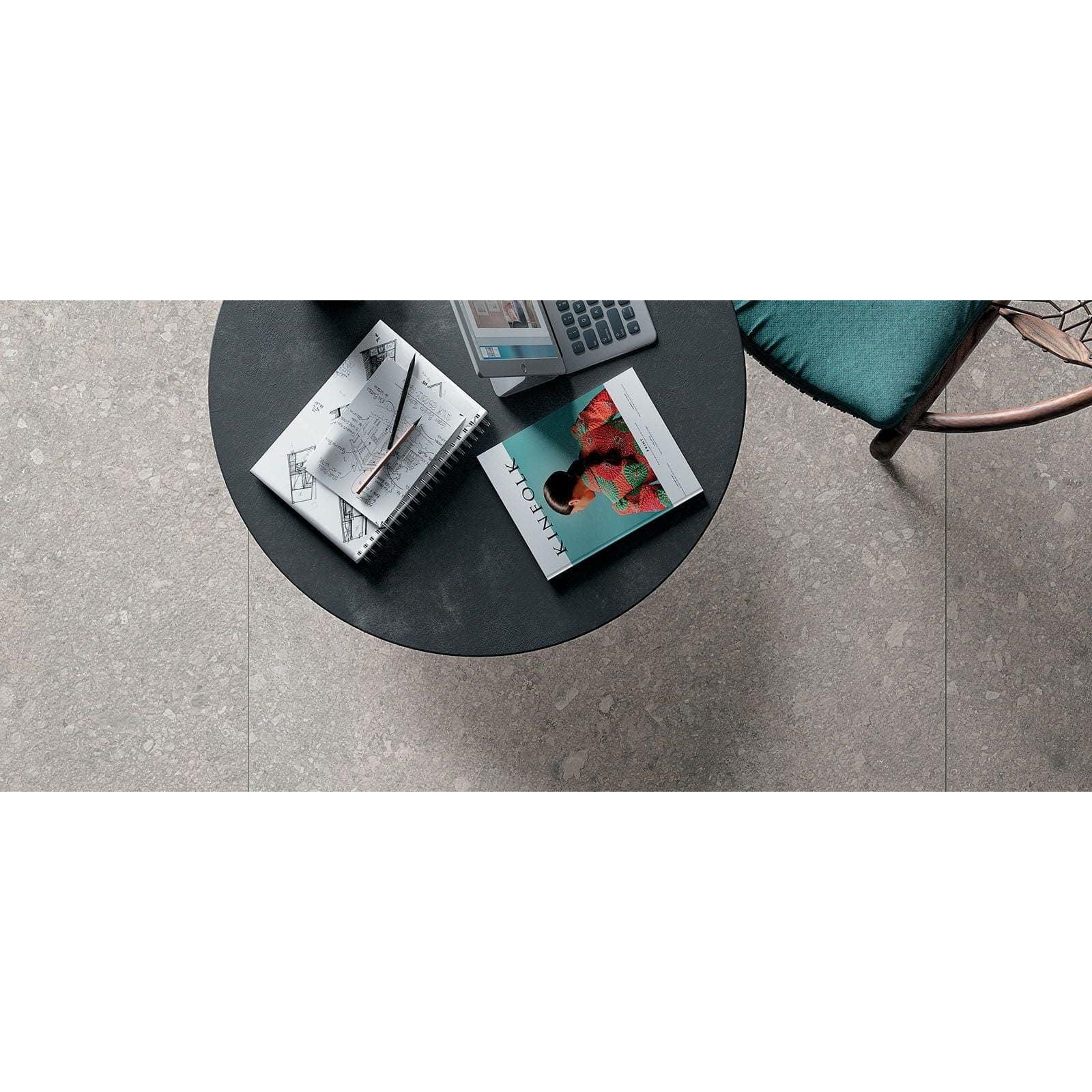 Norway Vit Matt light grey terrazzo-effect tiles with a black round coffee table