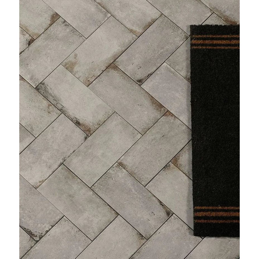 Gray concrete-effect herringbone porcelain tile flooring with subtle weathered texture in osterley porcelain white brick style