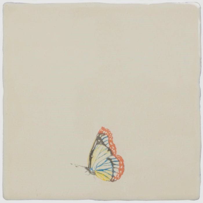 A delicate hand-painted butterfly with orange-edged blue veins on translucent wings on a cream ceramic tile in painted beauty pastel on palomino