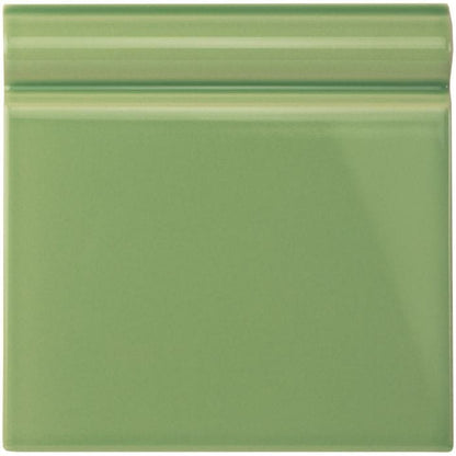 A square glossy sage green ceramic palm green skirting tile with a subtle raised border