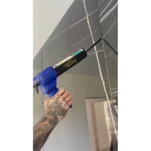 Blue and black caulk gun applies white Perflex P20 light beige sealant along seams of dark gray marble tiles