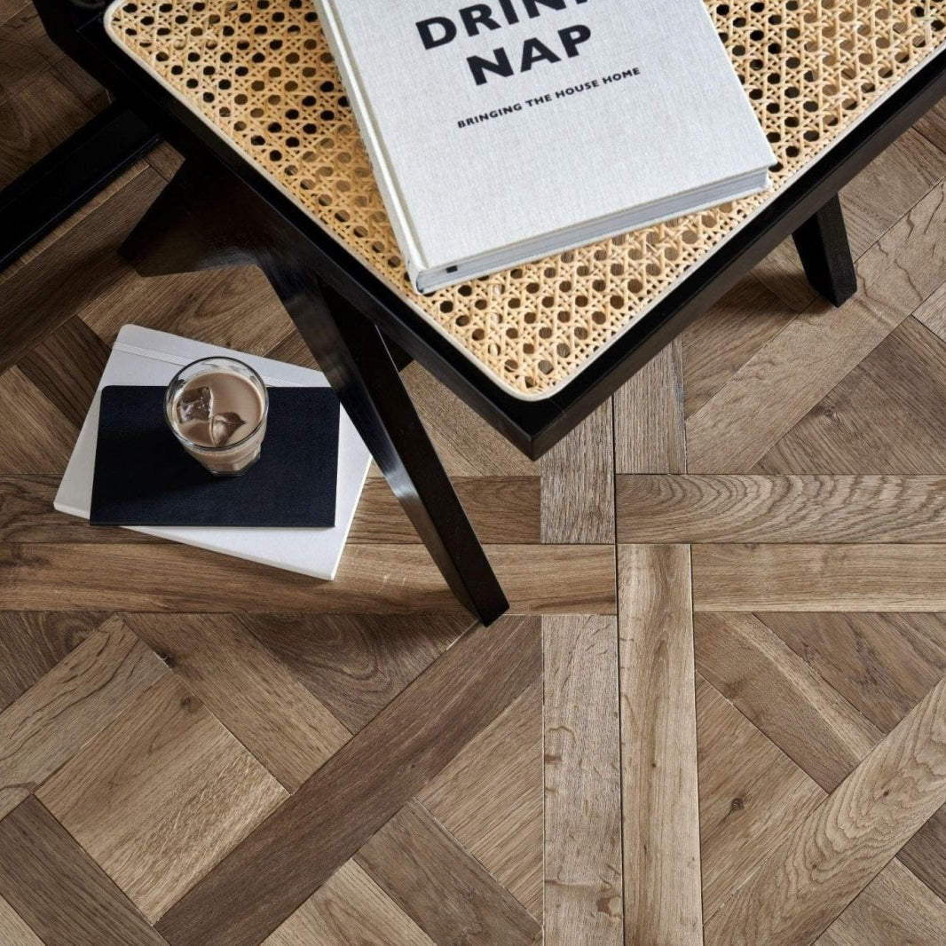 White hardcover Sandringham Royal Oak book with black text resting on a woven cane table