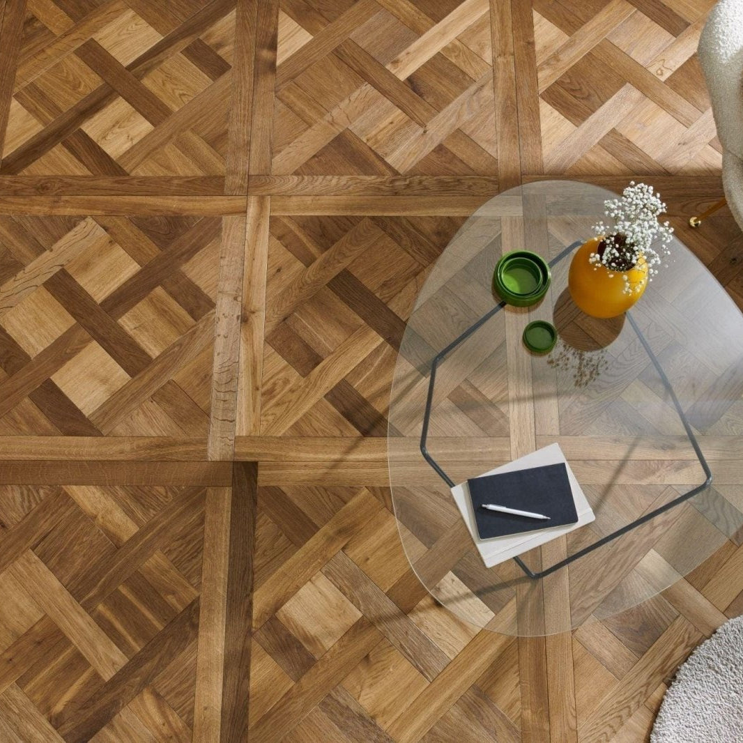 Wooden parquet floor in Woodpecker Sandringham Royal Oak Design Panels with a glass coffee table and decorative items.
