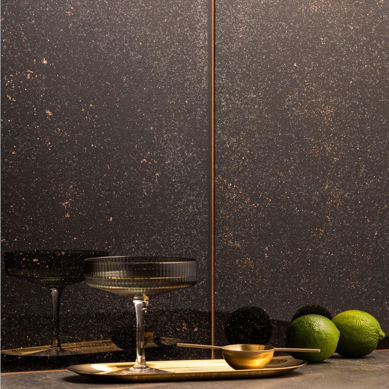 Solstice Decorative Glass black speckled glass tiles with a coupe glass on a brass tray