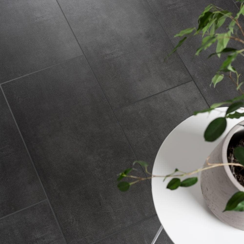 White round table with a potted plant on stark graphite porcelain tiles showcasing dark gray porcelain flooring