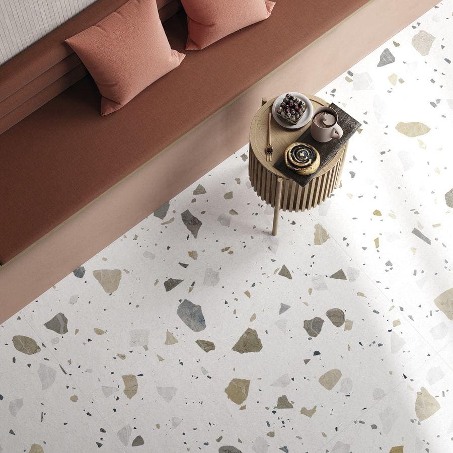 A small round table with vertical ridges and light wood finish paired with terrazzo colore light tiles