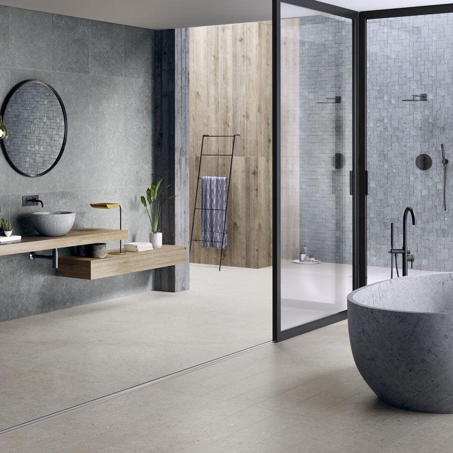 Gray stone freestanding bathtub shown with terrazzo coolstone greige tiles in a modern bathroom setting