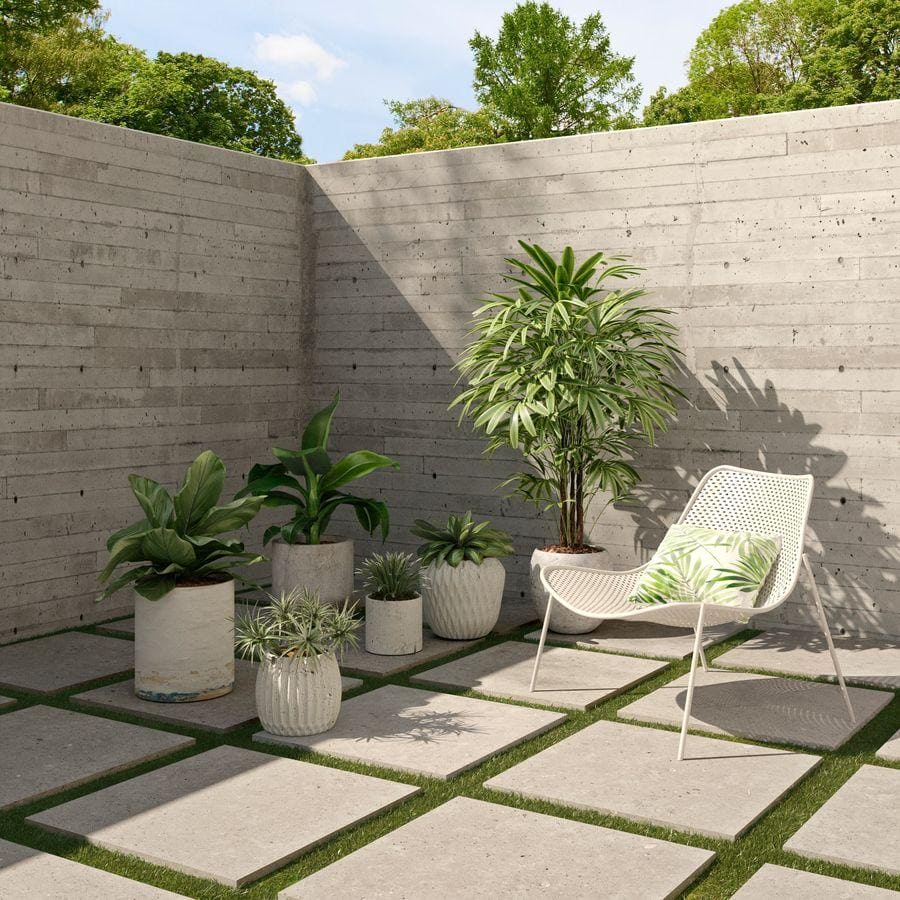 White woven mesh patio chair with green and white leaf cushion on terrazzo coolstone grey tile floor