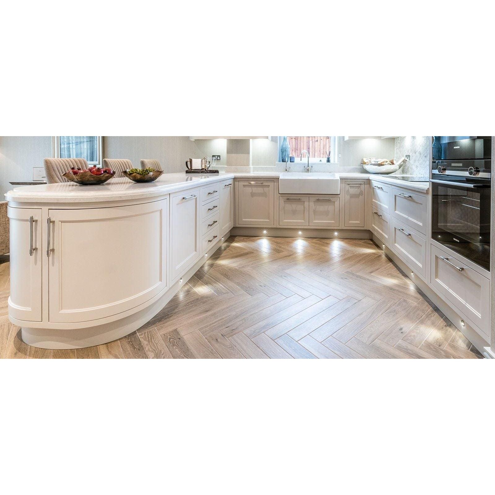 Cream-colored kitchen island with curved cabinetry and smooth light-toned stone countertop in tree-charme beige matt