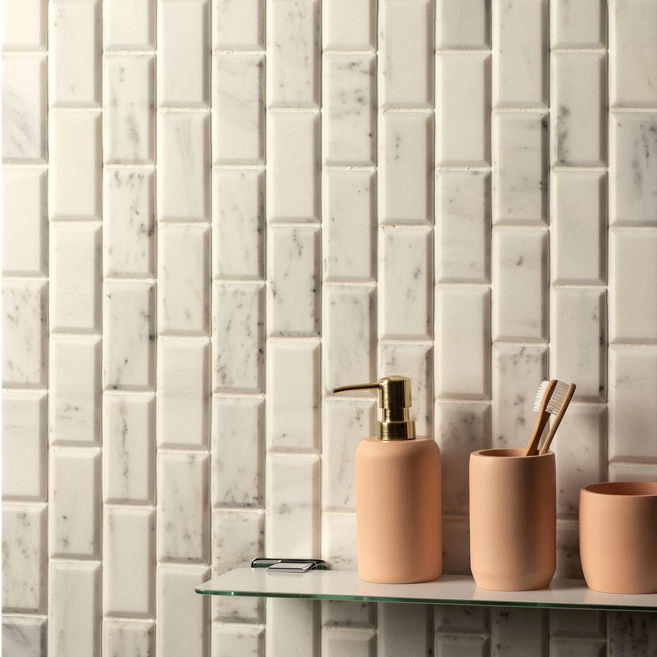 Beige ceramic soap dispenser with gold-tone pump shown with viano white polished bevel brickbond mosaic background
