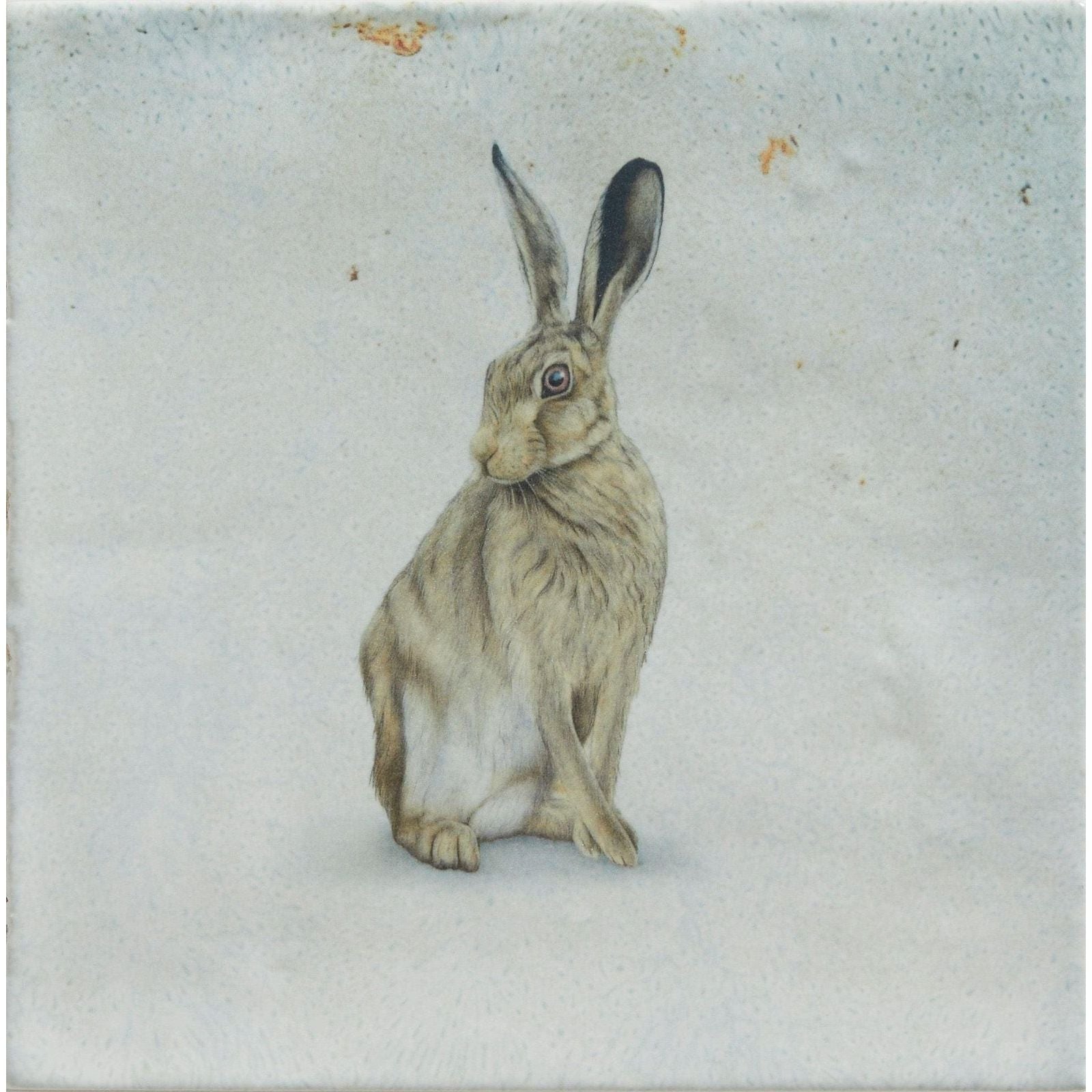 A detailed hand-painted illustration of a brown and grey hare on a textured light-grey ceramic tile wiltsire hares by joanna may